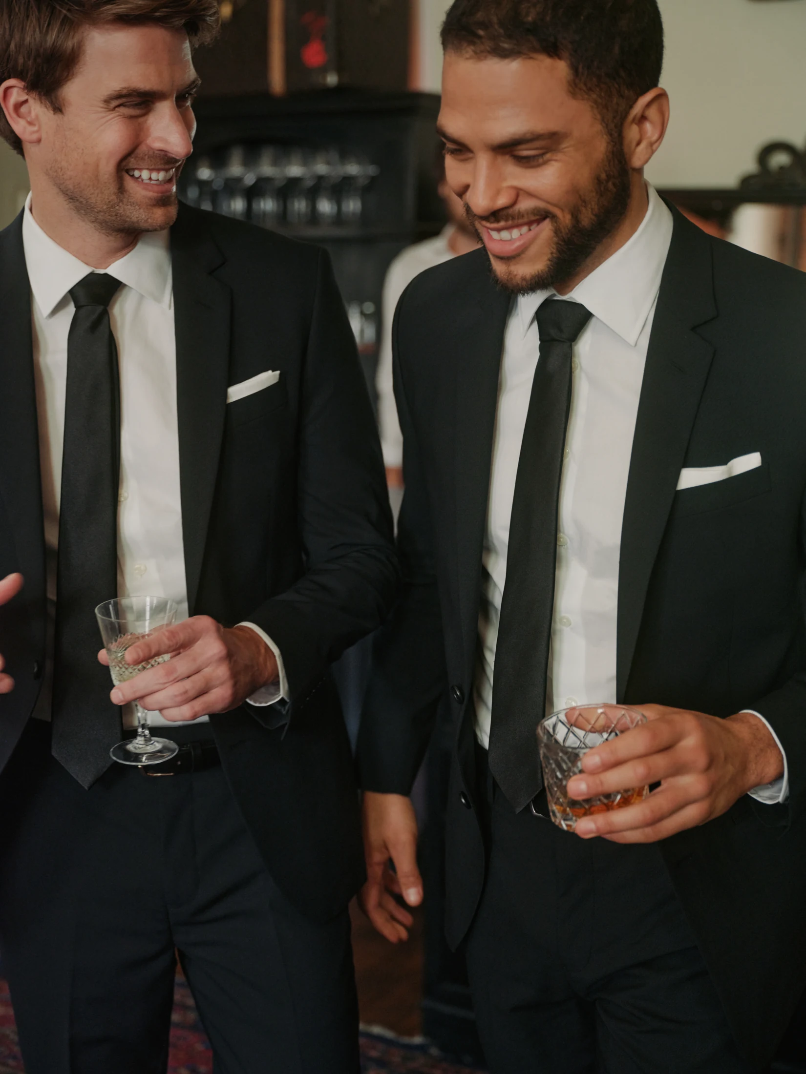 Two men in black suits holding drinks