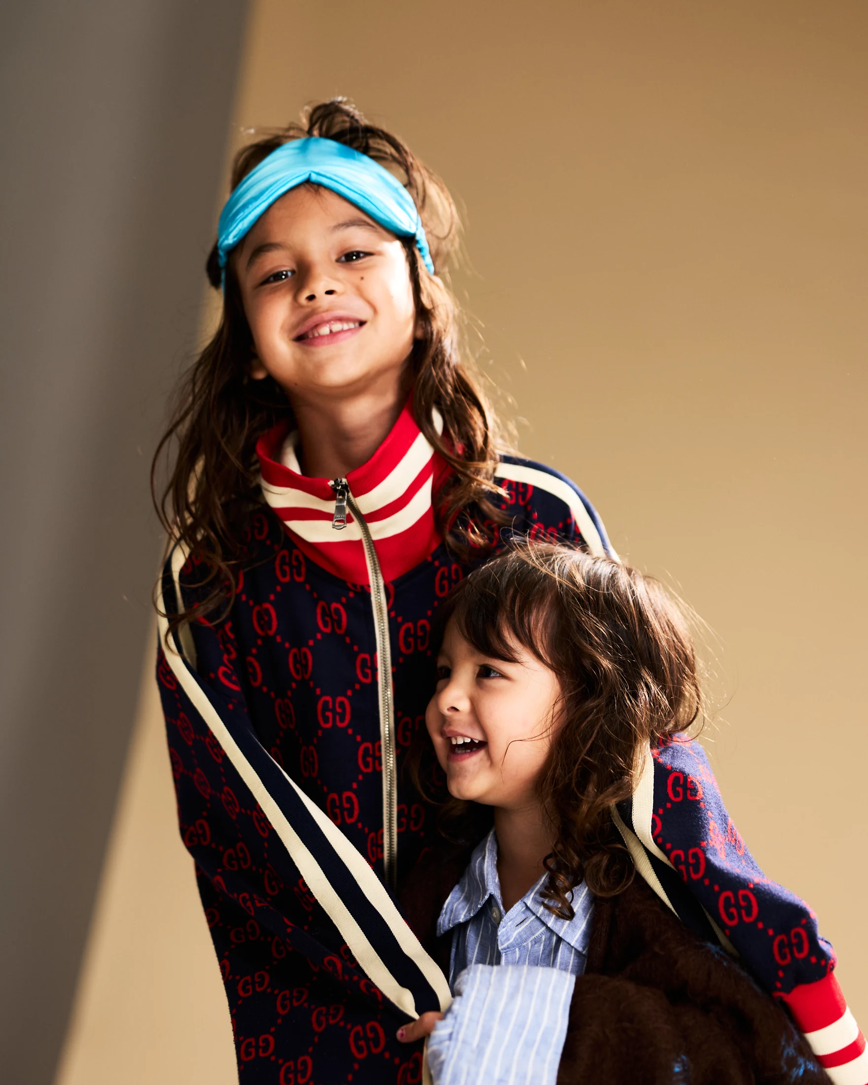 Two children together indoors, one wearing a blue sleep mask